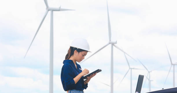 istock Women engineer using tablet for working on site at wind turbine farm 1309266692
