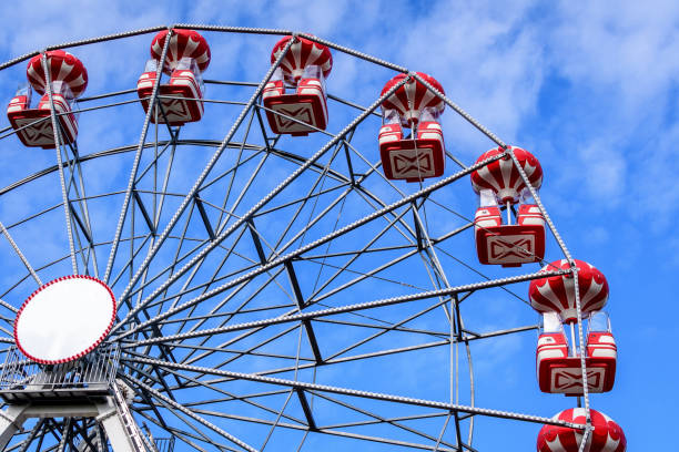 colourful children playground with giantred and white ferris wheel in a sunny summer day in herastrau park in bucharest, romania - ferris wheel fotos imagens e fotografias de stock