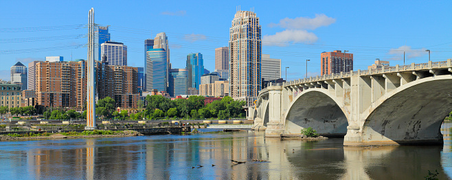 Daytime panoramic view of the skyline of Minneapolis and the Central Avenue bridge as seen from across the Mississippi river.