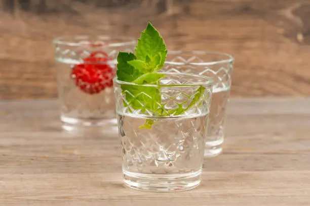 raspberry and mint flavored rum in shot glass on aged wooden table