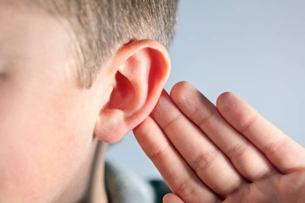 boy with hand on ear listening for quiet sound or paying attention - young ears imagens e fotografias de stock