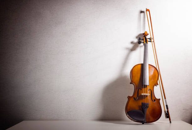 violín apoyado en un fondo de pared en blanco con espacio de copia para el concepto de música - chello fotografías e imágenes de stock