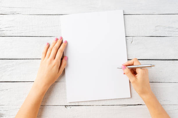 женские руки, пишущие на пустом листе белой бумаги. вид сверху - letter writing handwriting human hand стоковые фото и изображения
