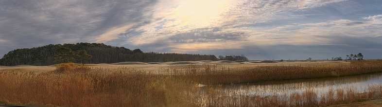 View across Rum Point Road on the eastern shore of Maryland across rime coated dunes at sunrise with the historic Rackliffe Plantation house in the Assateague Island National Park