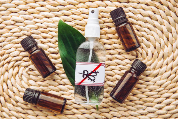 Homemade essential oil based mosquito repellent. Flat lay view of spray bottle surrounded by brown essential oil bottles on bamboo mat background. stock photo