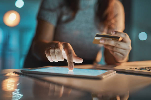 Making payments the simple way Cropped shot of an unrecognizable businesswoman using her tablet to make payments while working late in the office electronic commerce stock pictures, royalty-free photos & images