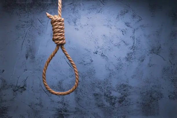 brown rope knot around neck hanging on old gray wall background, emotional stress and concept of suicide.