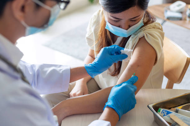 Woman taking a vaccine from his doctor Close up of a mid aged Asian woman taking a Covid-19 vaccine in his doctors office allergy medicine stock pictures, royalty-free photos & images