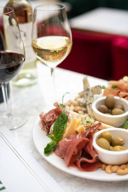 istock Assorted snacks. Cheese appetizer, cured meats, olives with two glasses of red and white wine in restaurant or cafe 1309301020