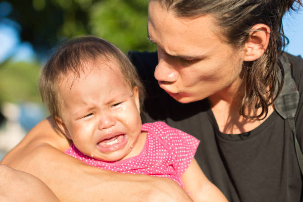 Weeping little female toddler weaping while her father comforts her outdoors.