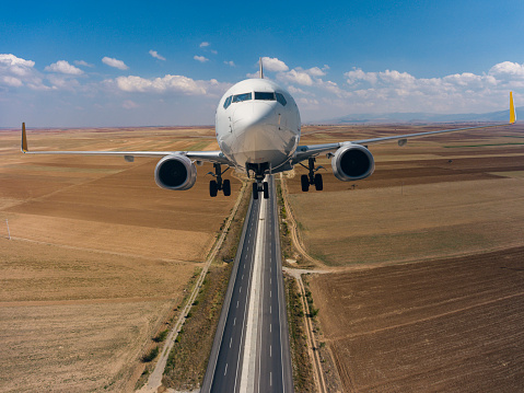 Passenger airplane flying over empty asphalt highway.