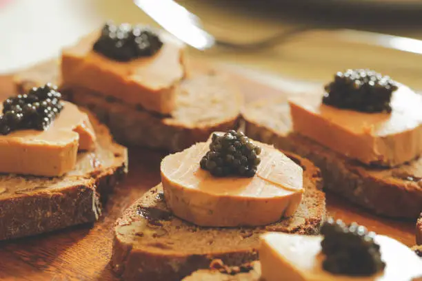Selective focus on sturgeon black caviar on foie gras and cutting bread, fevtive celebreation concept