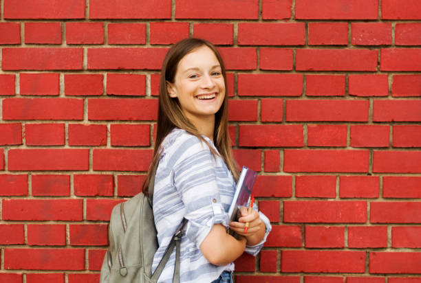 istock Smiling female college student standing in front of a brick wall 1309305408