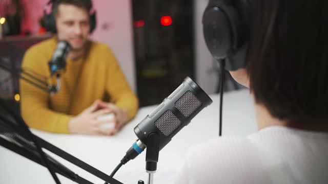Unrecognizable female host talking with young man in her radio talk show