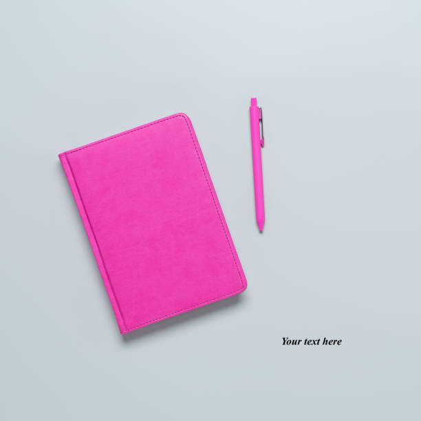 istock Pink notepad and pink ballpoint pen on a gray background. Creative layout. Blogger or freelancer workplace. Top view, flat lay. 1309309229