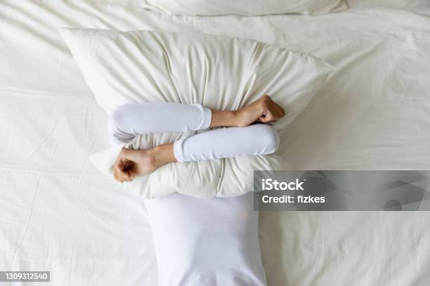Top View Depressed Woman Covering Face With Pillow Lying Alone Stock Photo - Download Image Now