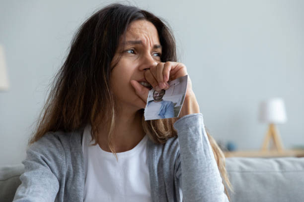 close up crying woman holding picture of husband, break up - former imagens e fotografias de stock