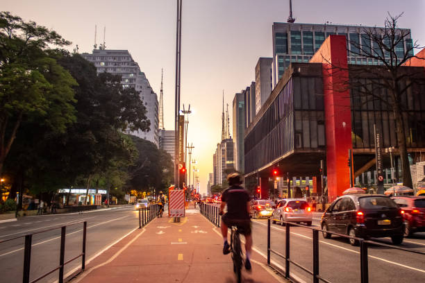 homme conduisant un vélo sur la piste cyclable de l’avenue paulista devant le musée des arts de são paulo - sao paulo photos et images de collection