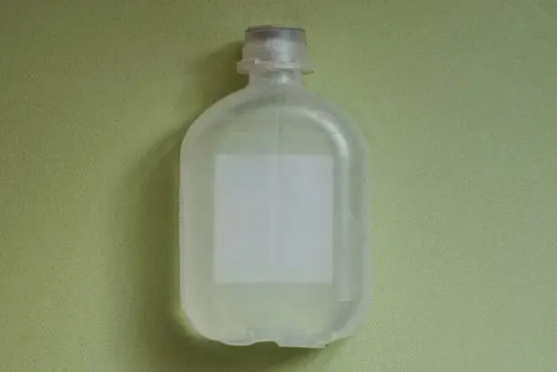 one white medical plastic bottle with water solution lies on a green table