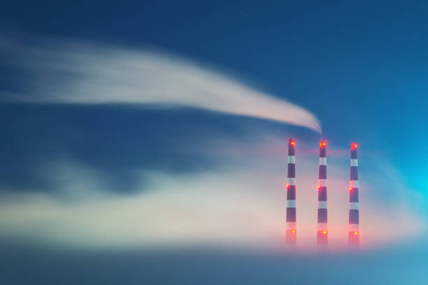 Fuel oil/natural gas electrical generating station chimneys in heavy fog at night.