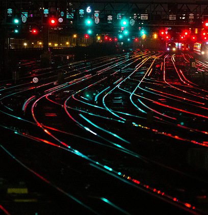 Night shot depicting interconnecting railroad tracks illuminated at night in the city at a railroad station.