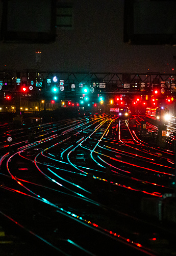 Night shot depicting interconnecting railroad tracks illuminated at night in the city at a railroad station.