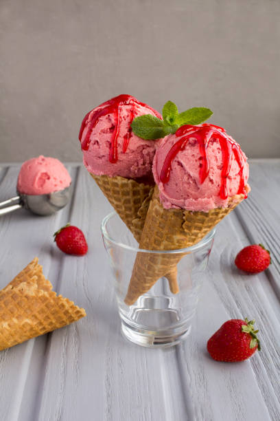 istock Strawberry ice cream in a waffle cone on the gray background. Close-up. 1309322971
