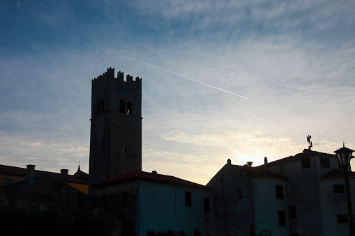 Motovun city tower silhouette against the evening sun. Medieval building with church.
