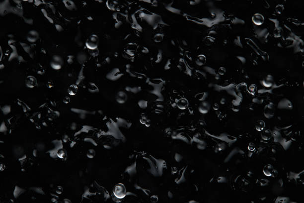istock Splashes and drops on the surface of the liquid. Abstract Black Background Liquid Texture 1309324489