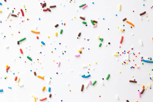 istock Colorful edible sugar sprinkles background - seamless pattern on white background. Spoons whith colorful sprinkles. 1309325284