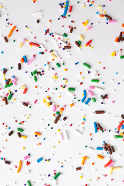 istock Colorful edible sugar sprinkles background - seamless pattern on white background. Spoons whith colorful sprinkles. 1309325286