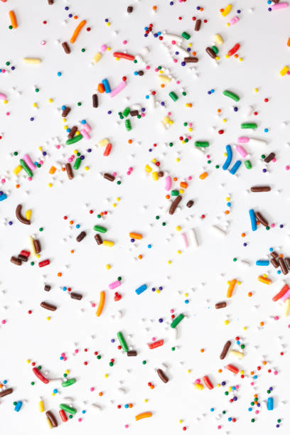 istock Colorful edible sugar sprinkles background - seamless pattern on white background. Spoons whith colorful sprinkles. 1309325762