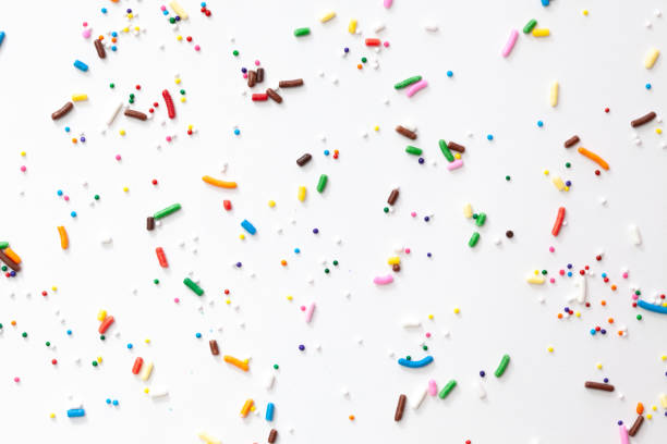 istock Colorful edible sugar sprinkles background - seamless pattern on white background. Spoons whith colorful sprinkles. 1309326458