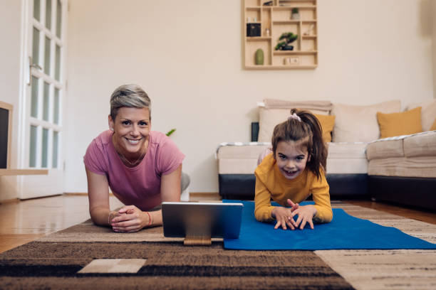 kleines mädchen und ihre mutter machen übungen, mit einem online-sport-kurs - yoga good posture women little girls stock-fotos und bilder