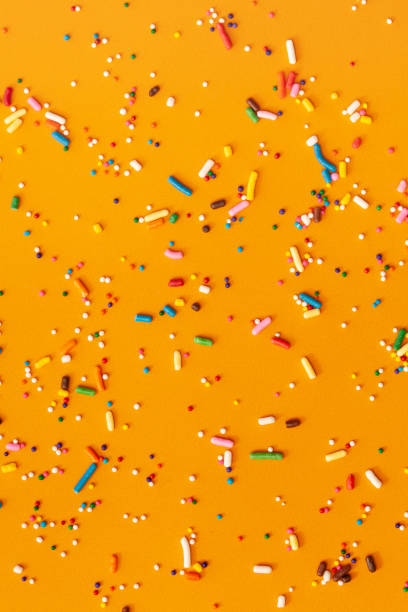 istock Colorful edible sugar sprinkles background - seamless pattern on yellow background. 1309326718
