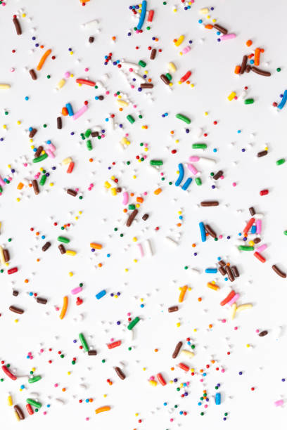 istock Colorful edible sugar sprinkles background - seamless pattern on white background. Spoons whith colorful sprinkles. 1309326795