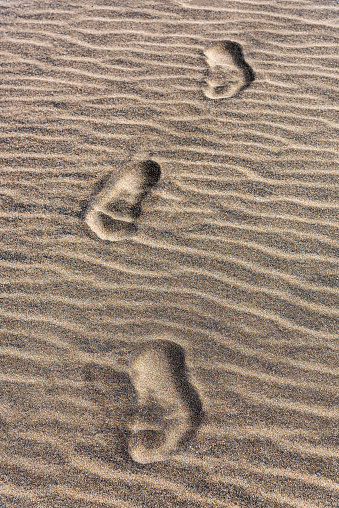 Footprints on the wave pattern sand background