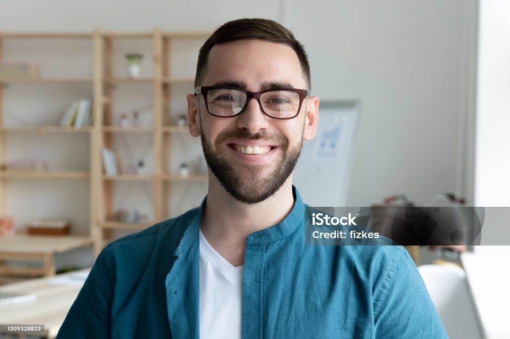 Headshot portrait of smiling male employee in office Close up headshot portrait of smiling young Caucasian businessman in glasses posing in office. Profile picture of happy millennial male employee or worker in eyewear at workplace. Employment concept. Profile View Stock Photo