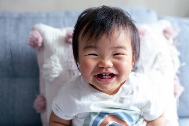 Adorable baby laughing Portrait of an adorable baby of Asian descent laughing while looking directly at the camera. The baby is teething and you can see he has four teeth. baby first tooth stock pictures, royalty-free photos & images