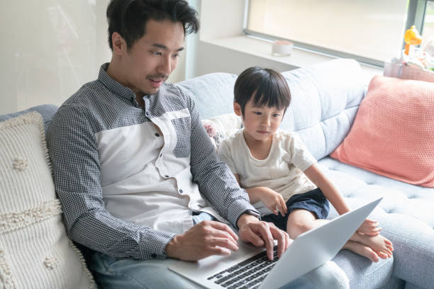 istock Dad working on laptop computer with preschool age son 1309328845