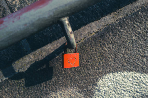 a red padlock engraved with a heart hangs on a handrail of a staircase