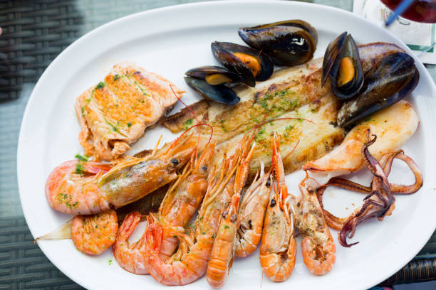 istock Seafood with fish, king prawns, mussels and octopus on a white plate 1309330209