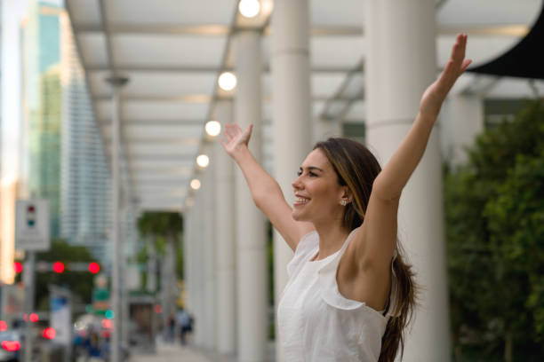 donna d'affari eccitata per strada che celebra un risultato con le braccia alzate - donna profilo braccia alzate foto e immagini stock