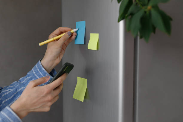 istock a person makes notes on a sticker on a refrigerator, a reminder from a phone 1309335168