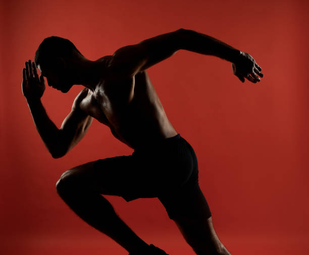 Handsome unrecognized athlete in action isolated on red background of a studio