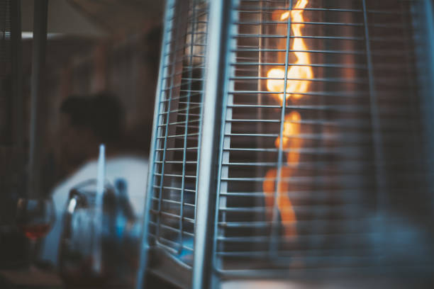 Street gas heater, flame, tilt-shift A true tilt-shift photo of a street gas heater for a patio with a flame of fire inside, with a selective focus on the part of a protective metal grid garden feature stock pictures, royalty-free photos & images
