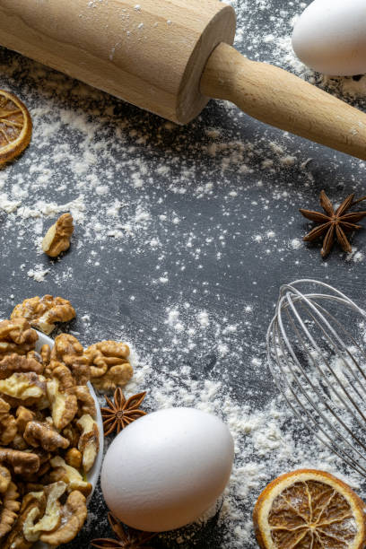 istock Bakery background frame. Fresh food ingredients: flour, eggs, nut and star anise, orange on black chalkboard background for bread. Still life captured from above, top view, flat lay. 1309339280