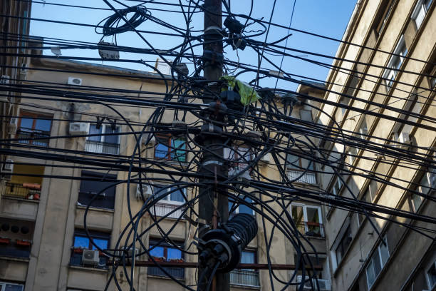 Bucharest, Romania - March 11, 2021: Many electricity, internet and communications cables hang out on a pillar in Bucharest.