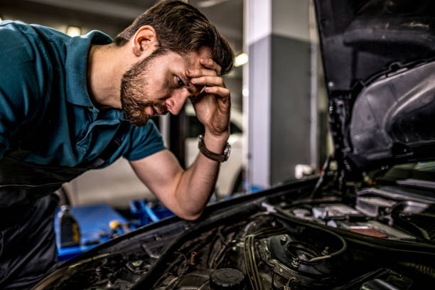 istock Worried mechanic examining engine problems in auto repair shop. 1309348965