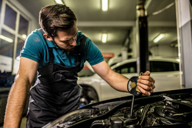 istock Mechanic checking antifreeze level on vehicle at car workshop. 1309349895